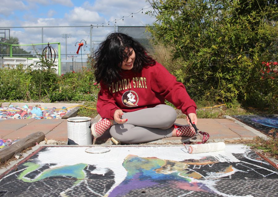 Senior Isabella Pfeiffer paints a mural for Astronomy Club in Marjory’s Garden on Dec. 19. Photo by Nyan Clarke