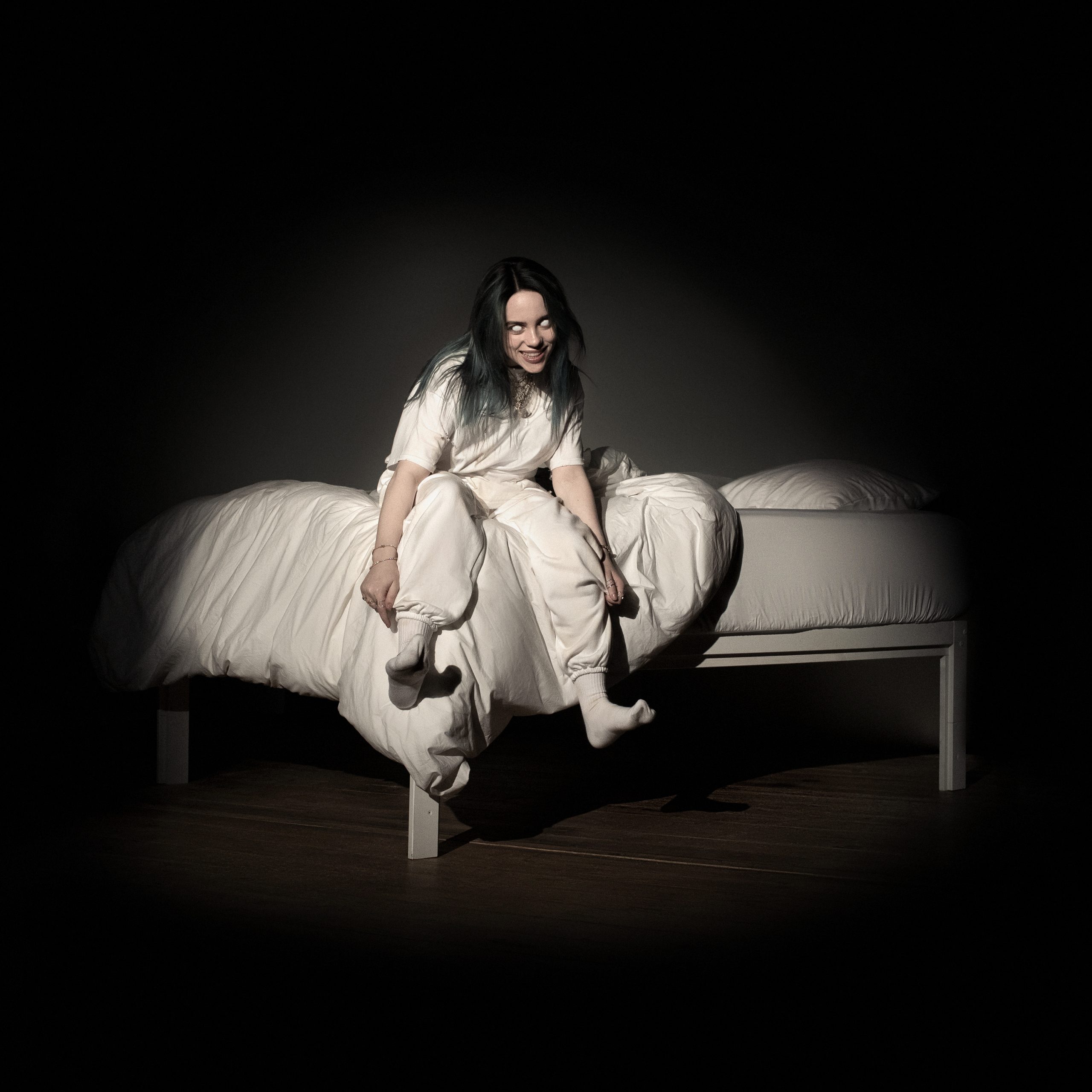 Billie Eilishs cover for her new album WHEN WE ALL FALL ASLEEP WHERE DO WE GO? featuring herself sitting on a bed, smiling and her eyes whited-out