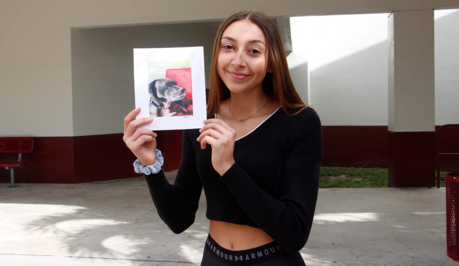 Junior Olivia Blaker poses with her realistic drawing of a dog.