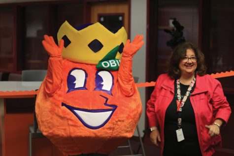 New and Improved. Media Specialist Diana Haneski, along with the mascot of the Orange Bowl Committee, Obie the Orange, welcome students and staff to enjoy the newly renovated media center on Monday, Nov. 18. In order to match the new look, the addition to the media center was named the STEAM Lab. Photo by Darian Williams