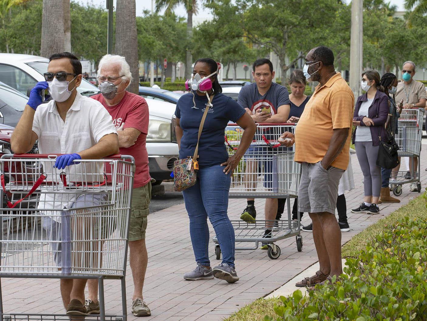 Seven out of nine customers in a long line outside Costco, wear protective masks, Friday in Royal Palm Beach. The discount wholesaler had supplies of toilet paper, paper towels, tissues, chicken, eggs and milk, but no hand sanitizer. [ALLEN EYESTONE/palmbeachpost.com]