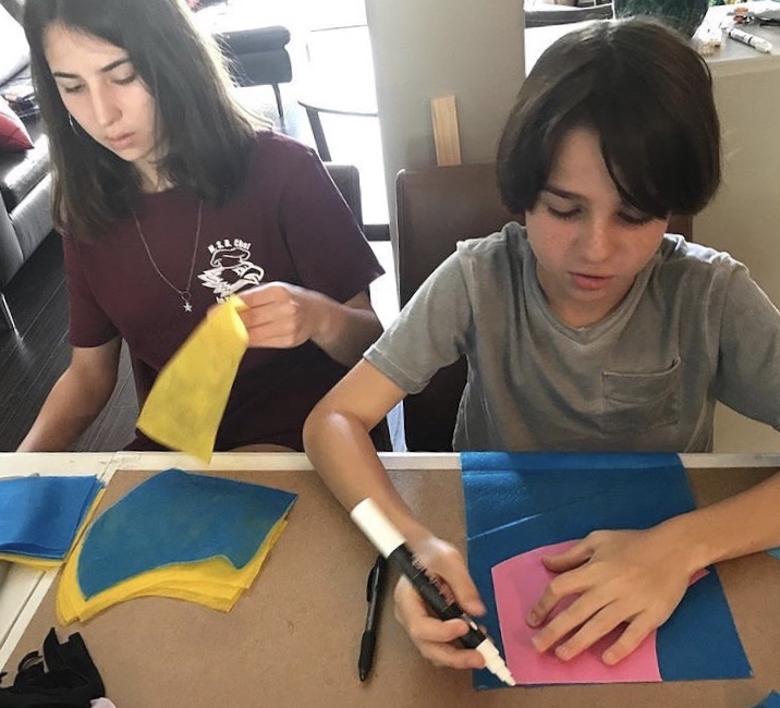 Blanco-Bulhoes outlines and cuts fabric for the Cupid Covid masks with her younger brother. 
