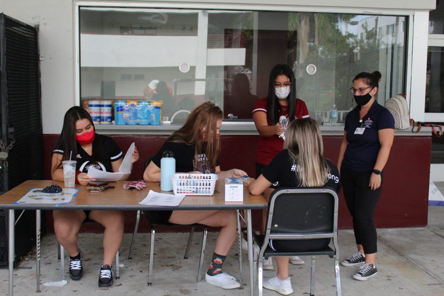 Volunteers check in a student athlete at a voluntary conditioning session. Student athletes must be submit to a health screening before entering the campus for conditioning. Photo by Destiny Cazaeu