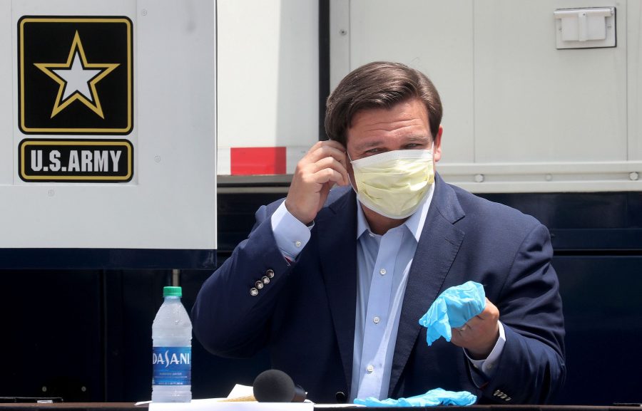 Florida Gov. Ron DeSantis removes his face mask as he prepares to talk to the media on April 8 at the Miami Beach Convention Center.  The city of Miami Beach and the U.S. Army Corps of Engineers plan to convert the facility into an alternate care facility.