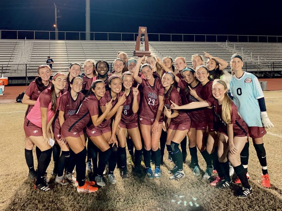 After the MSD girls varsity soccer team beat the Coral Glades Jaguars by a score of 4-0, the team poses for a photo on the field with the District Championship trophy.