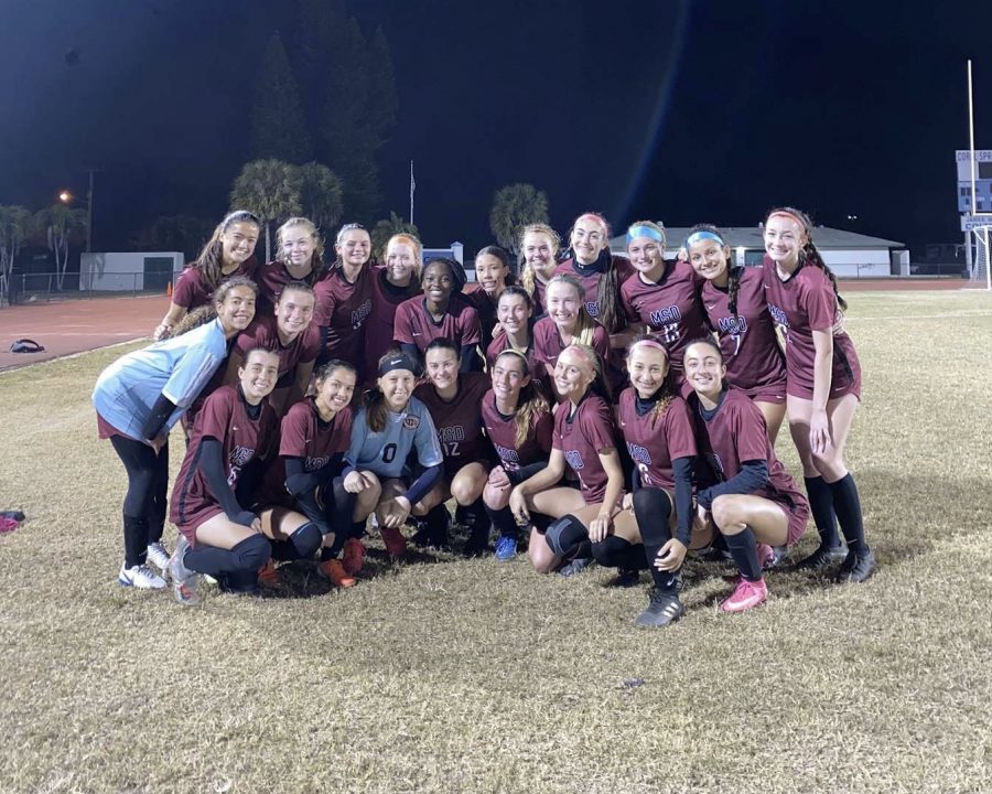 The+MSD+girls+varsity+soccer+team+groups+together+for+a+team+photo.+The+girls+arrange+themselves+so+that+every+teammate+is+visible+and+smiling+in+celebration+of+their+victory.
