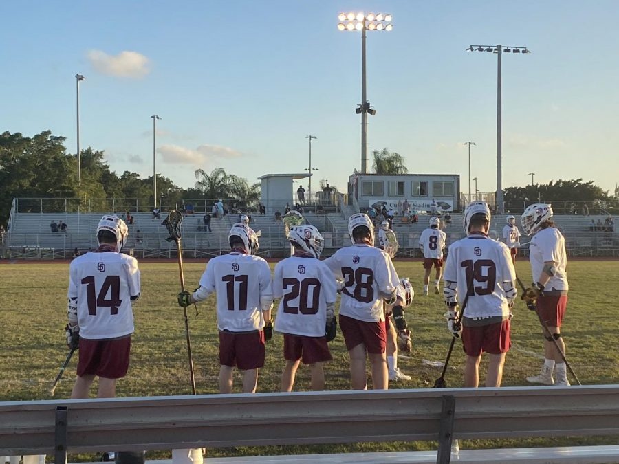 Sideline scouting. Players of the MSD mens varsity lacrosse team stand on the sidelines of Cumber Stadium after finishing their pregame warm-up in a game against Coral Springs. Photo by Reece Gary