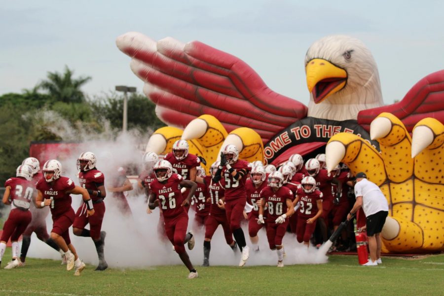 The Marjory Stoneman Douglas varsity football team runs onto the field for their third game of the season. Despite a strong start, the Eagles were unable to continue the game due to harsh weather conditions.