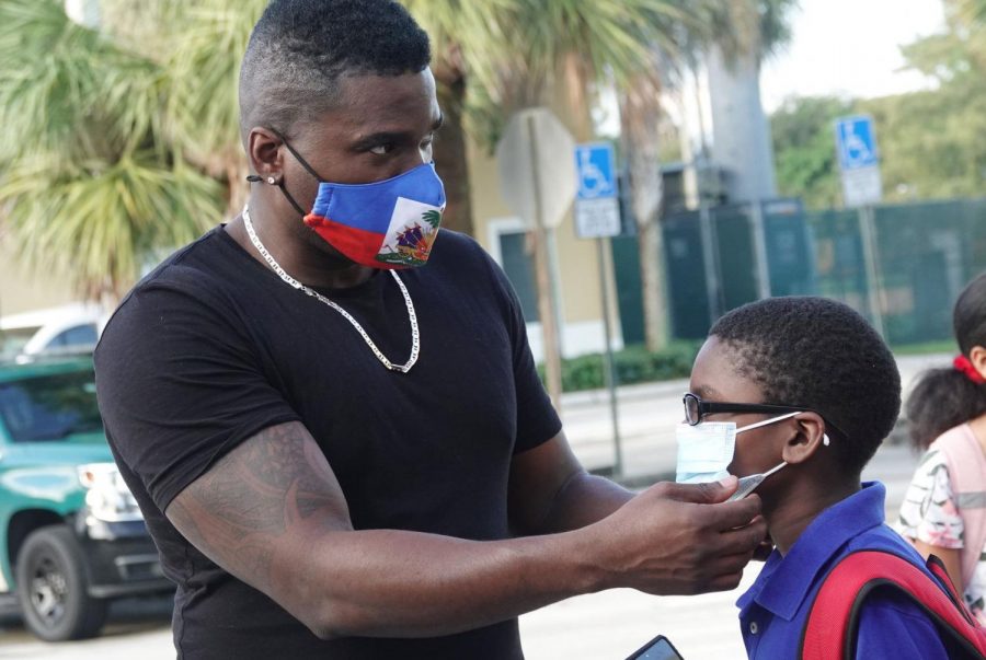 Guyano Dulcio helps his son Tayden, age 8, with his mask before school on Sept. 22 at Tamarac Elementary School. Broward schools continue with a no opt out mask mandate in defiance of Gov. DeSantis. Photo courtesy of Joe Cavaretta