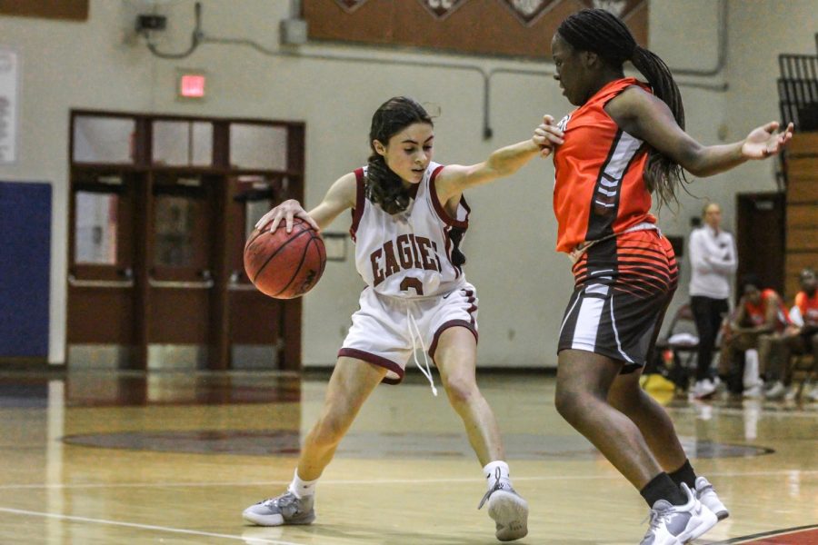 Defending the hoop, point guard Stella Marvel (3) dribbles the ball away from an opponent player from Piper High School.