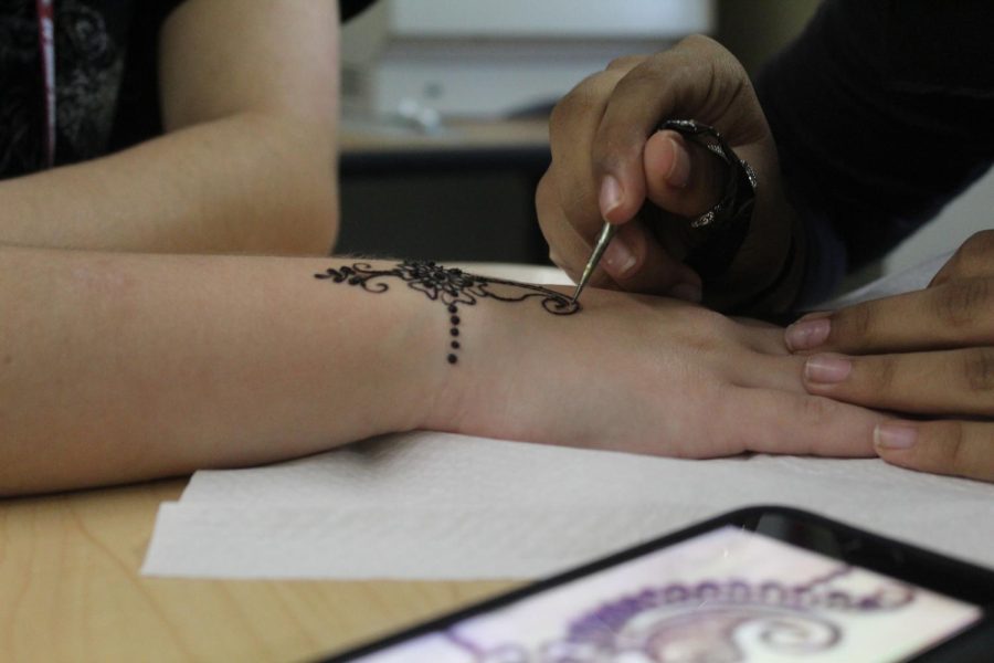An Artist at Work. Sophomore Manahil Kashif creates a henna design on a fellow student during study hall. 