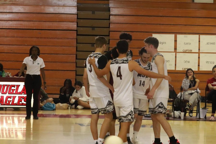 The mens varsity volleyball team huddles together in rejoice after scoring another ace.