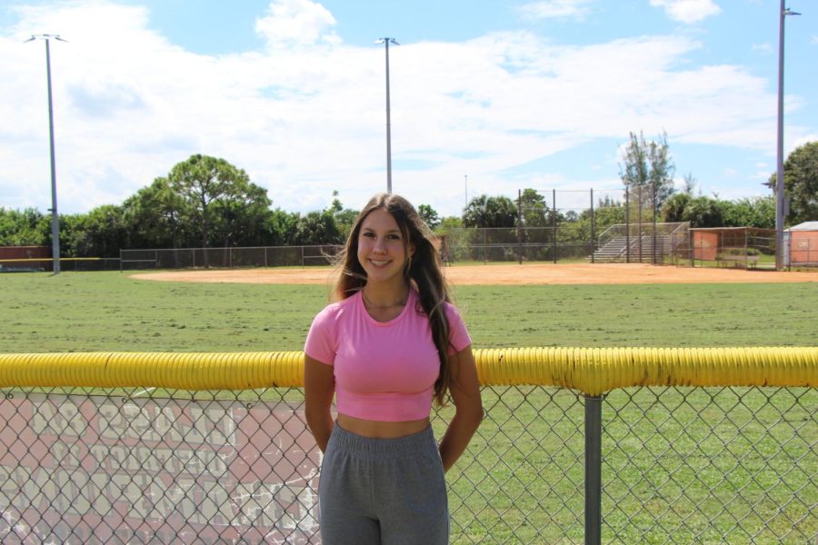 Senior+Olivia+Alvarez+stands+in+front+of+the+Marjory+Stoneman+Douglas+softball+field%2C+her+home+away+from+home+for+the+past+four+years.+She+has+committed+to+Rollins+College+for+softball+next+year.