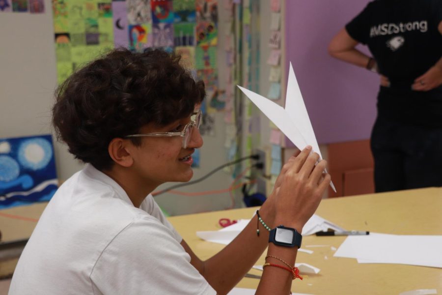 FOLD. FOLD. REPEAT. Junior Ayur Patel folds a paper airplane and makes sure it is symmetrical. The window installation, according to art teacher Randee Lombard, will take hundreds of airplanes to create so the students must work quickly and effectively to make them all. 
