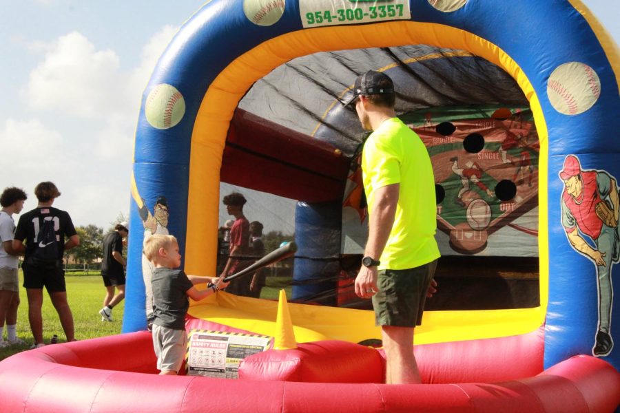 Young walker practices their swing in an inflatable baseball practice pit. Various inflatables were set up for the younger participants of the race to enjoy.