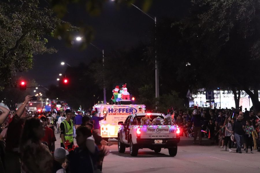 A truck with inflatables on the roof drives past the sea bystanders on the street. Businesses who wanted to be in the parade were able to advertise decorating their company trucks.