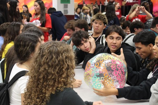 A DECA general member reads an icebreaker question that is written on a beach ball aloud. As part of this years first DECA social, students who attended played fun games to aid them in getting to know their peers.