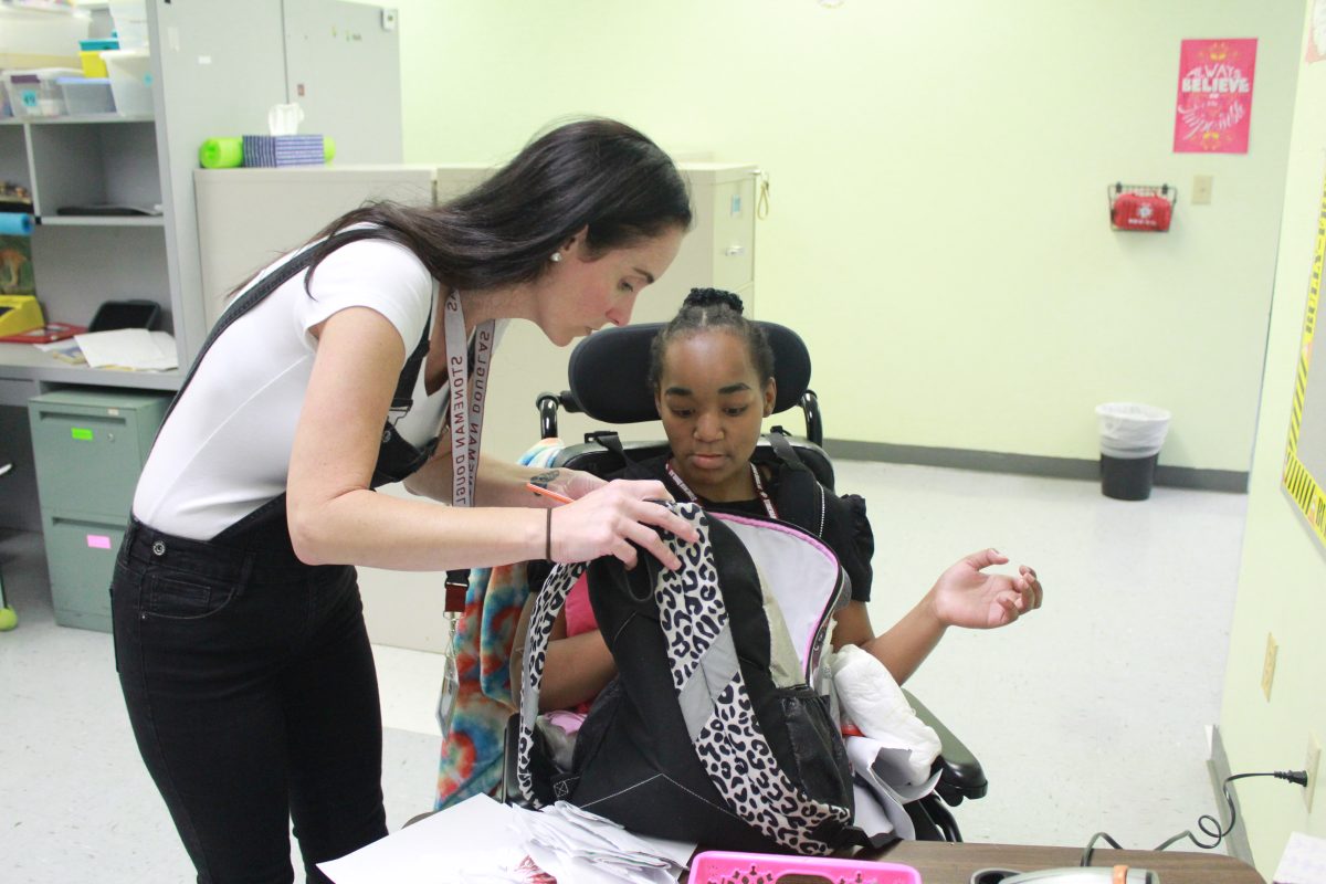 Christina Ferrara helps a student take supplies out of her backpack. The Exceptional Student Education program gives disabled students a space to thrive academically and have their needs met.