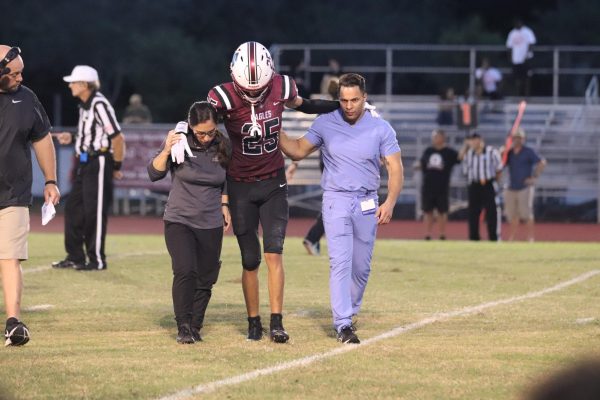 Quick off the field. Defensive Back Daniel Barraza (25) walks off the field with help of the two trainers after tearing his ACL in the first game of the season. Barraza was out the whole 2022-23 season. “I don’t really remember this, but I remember my knee buckl[ing] and getting up, and I couldn’t walk,” Barraza said. “My heart sank; at that moment, I knew it was wraps.” 