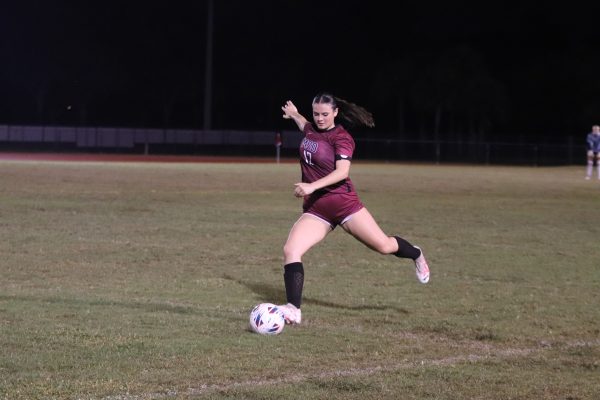 Midfielder Lilly Conn (12) gets ready to kick the ball on a free kick following a penalty by Pompano Beach High School. She scanned the field and looked for an open teammate by the opponents goal to pass it to.