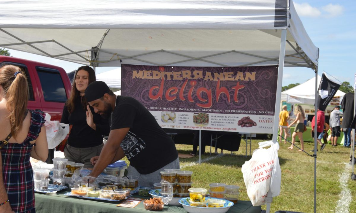 Assistants for the Mediterranean Delight stand aid customers during the farmers market hosted on Sunday, Nov. 19. The stand sold authentic Mediterranean food and had plentiful options.
