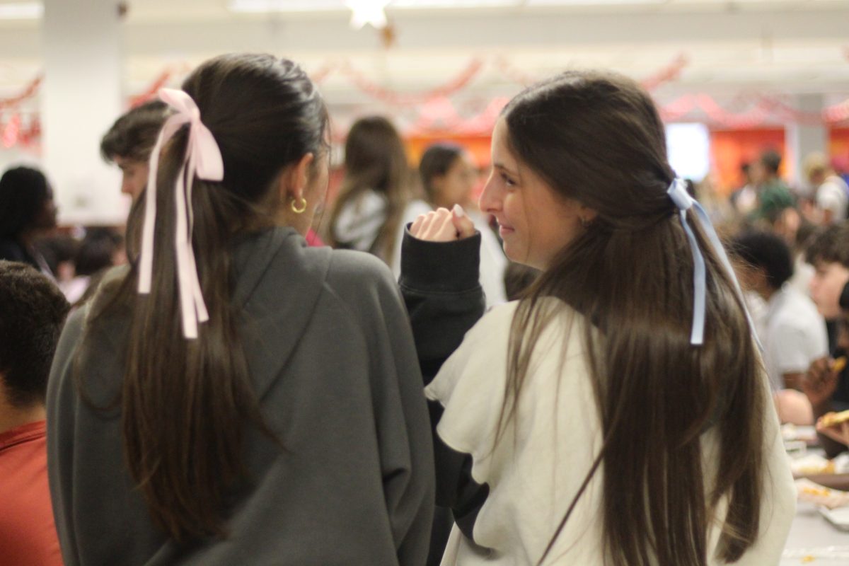 Bringing back the coquette style, juniors Courtney Solinksy and Taylor Bretz talk to each other while wearing their colored bows. Their bows were bought on Amazon and can be purchased in many different colors.