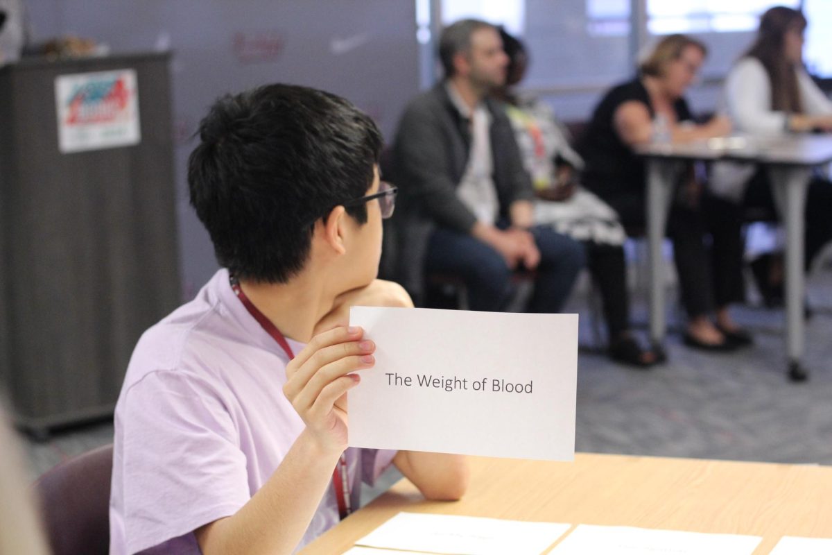 Sophomore Marc Lam holds up his card to answer the given question. This round was a part of the Battle of the Books competition, in which students from schools across the county answered trivia questions regarding their assigned books.