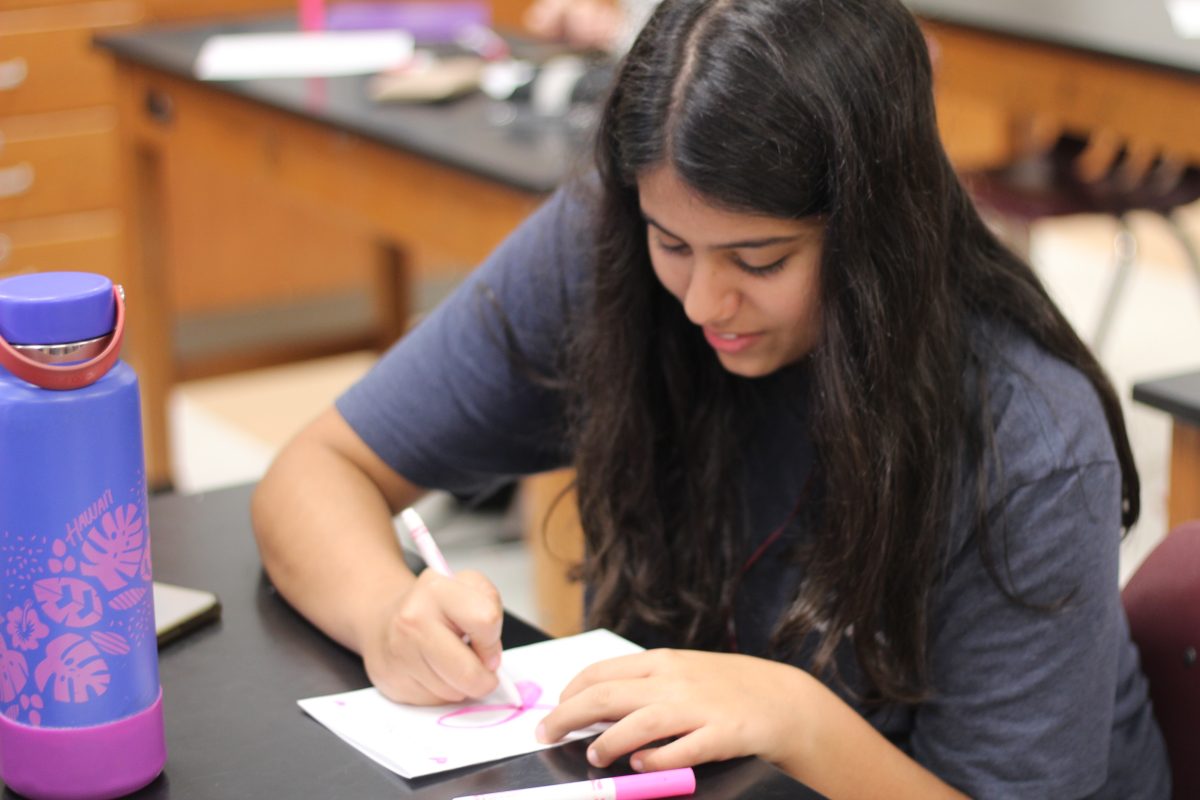 Freshman Anabella Karam draws a pink ribbon during the Health Occupations Students of America meeting on Monday, Oct. 28. They went over breast cancer as well as its effects and made cards for breast cancer patients. "I joined [HOSA] because I thought it would be a great opportunity to learn new things and compete in a field of study that interests me," Karam said.