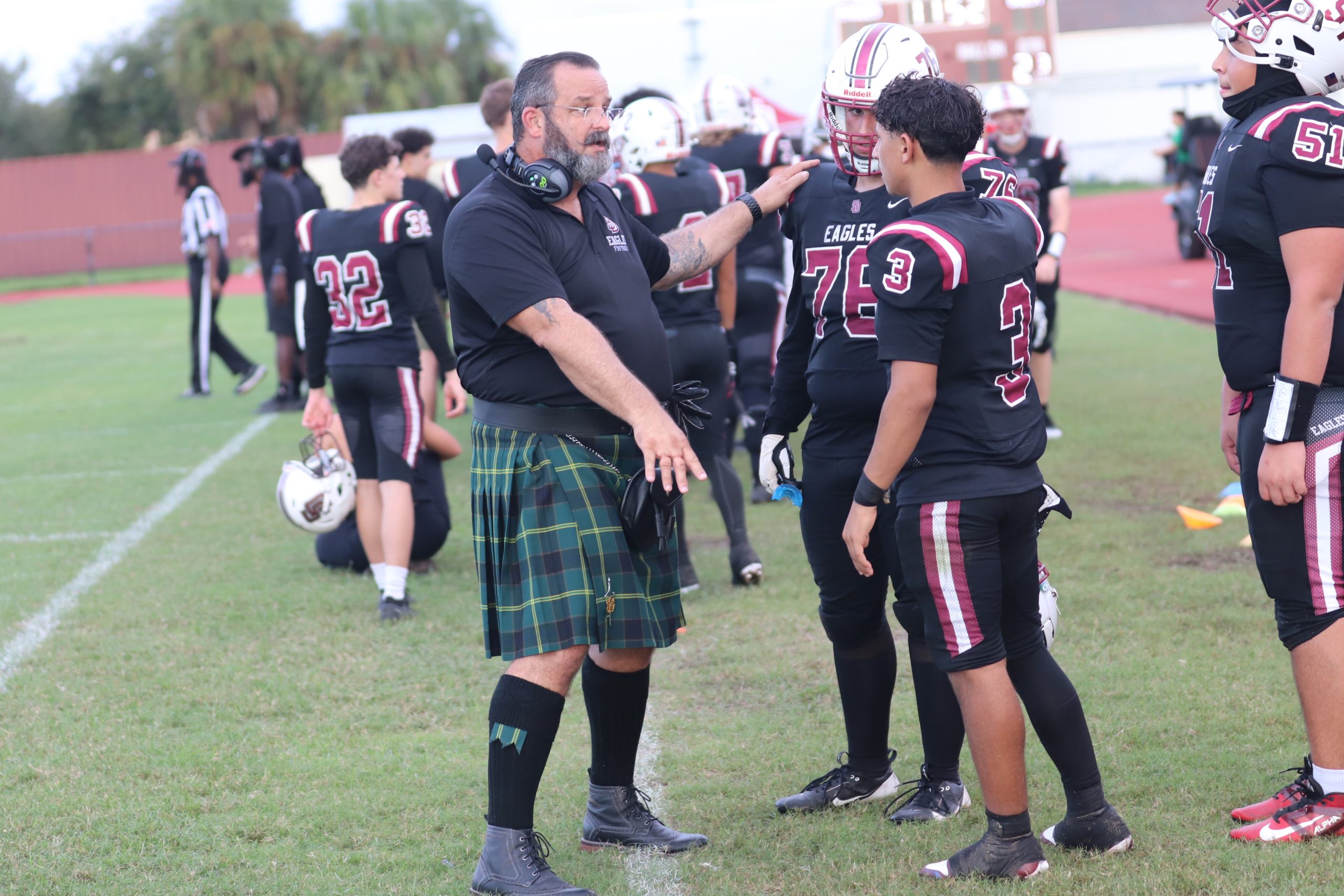 Offensive line coach Kelly Simon instructs running back Anthony Diaz (3) and Austin Mares (76) on what to do for the next play. MSD's Homecoming football game was played on Friday, Sept. 20, at 6:00 p.m. at Cumber Stadium. The Eagles played against Boyd Anderson High School where they suffered a loss of 41-7. "I felt that our effort as a team was lacking," Diaz said. "We definitely need to improve for upcoming games."