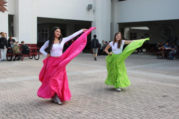 Smiling at the audience, juniors Valeria Gutierrez and Sofia Soto fan out their skirts while performing a folklore Mexican dance on Tuesday, Nov. 12 for Welcome to America's Cultural Festival. The festival was held all week and showcased different cultures through dances of origins from Mexican to Brazilian.