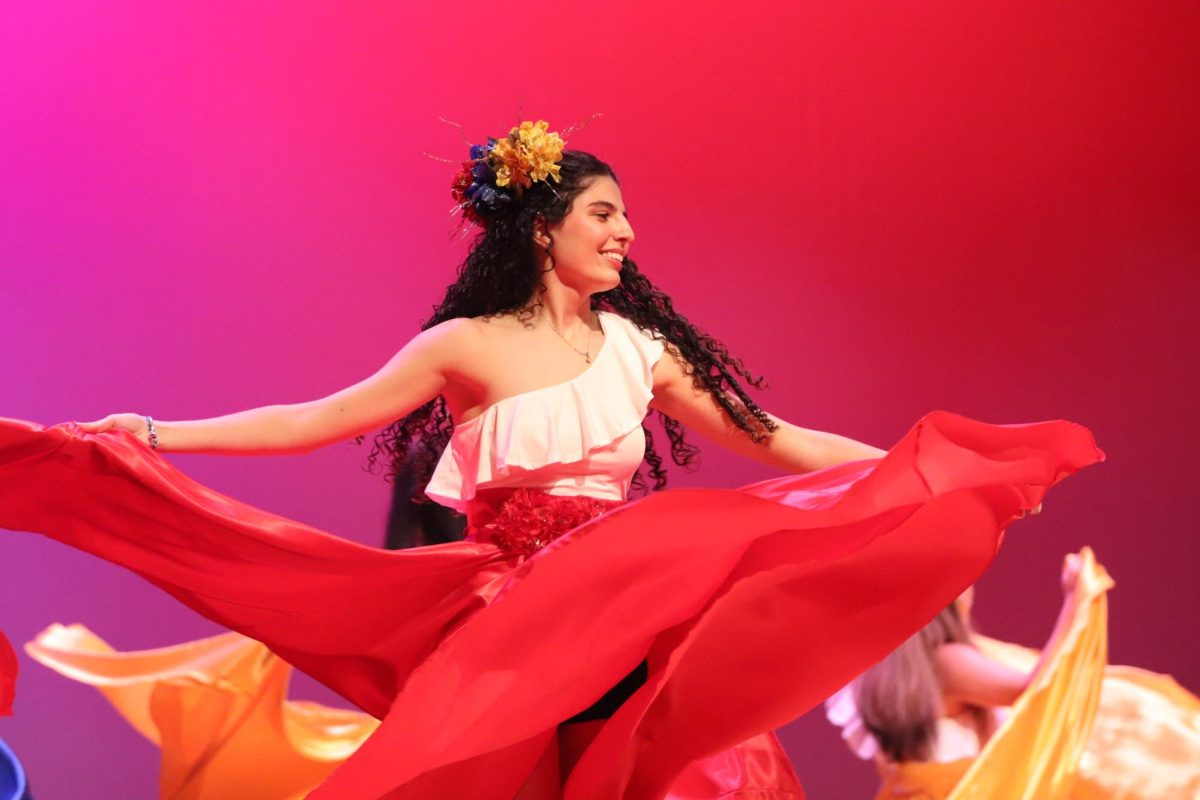 Senior Josefina Lamaison twirls her skirt during the cumbia dance. The cumbia dance honored Colombian culture.