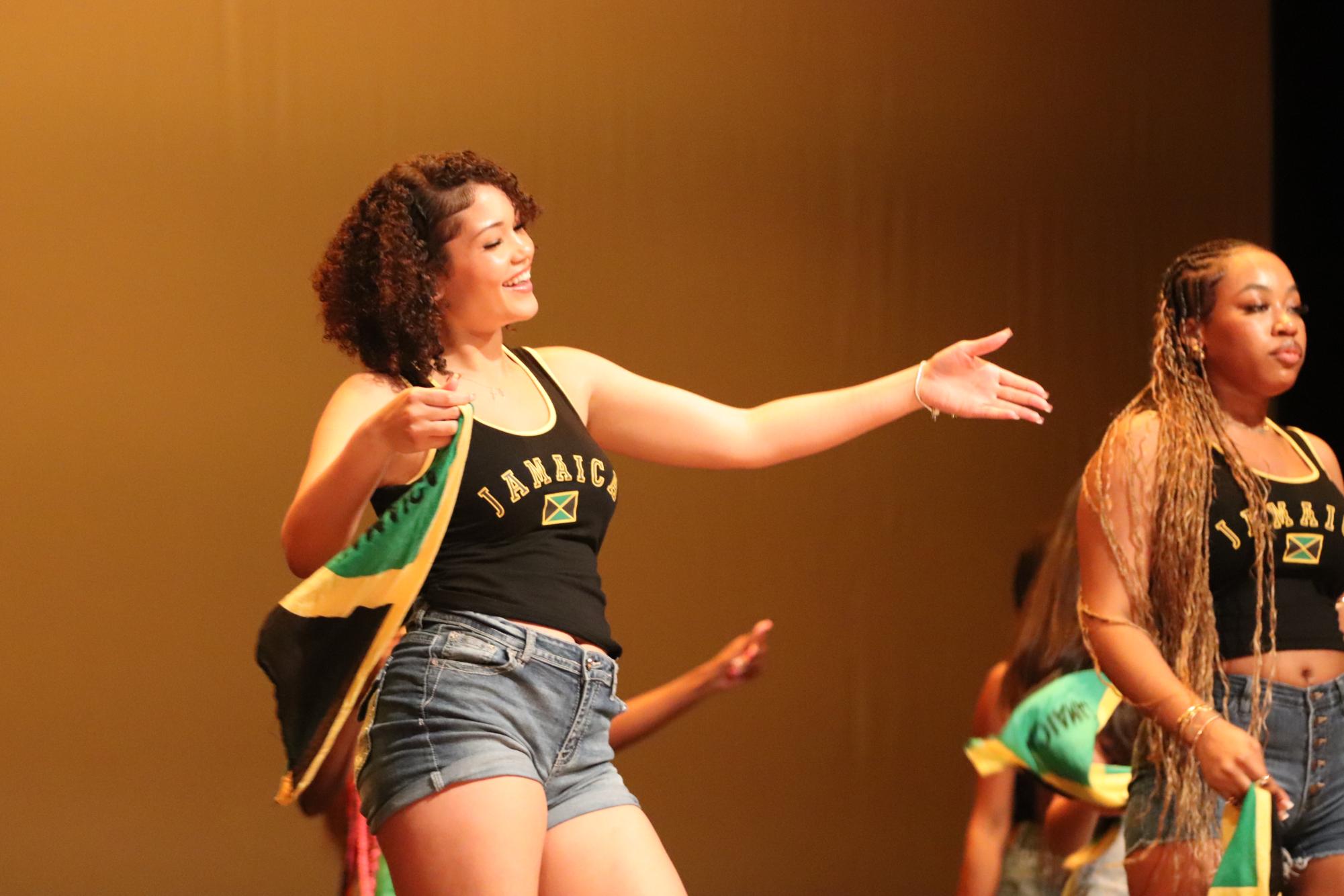 Senior Grace Bird dances with the Jamaican flag during the Jamaican dance in the Multicultural Show. Bird choreographed the dance this year.