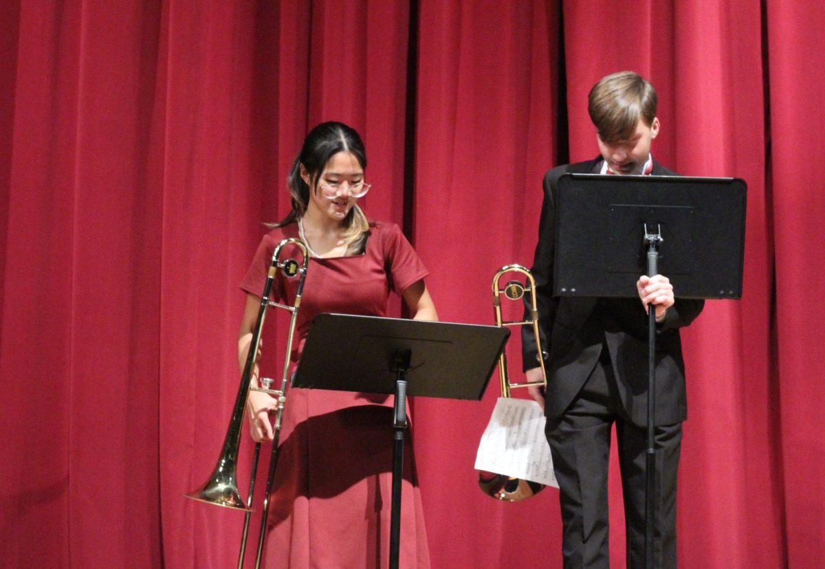 Juniors Yoyo Li and Maximas Klimov set up for their performance with the Low Brass Ensemble during the band's winter concert on Friday, Dec. 13 in the auditorium. The juniors both played trombone in the piece "Autumn Leaves" by Frank Sinatra. "My favorite song performed was probably Illumination," Li said. "I like faster paced songs, and it was personally more fun to play compared to the other two."