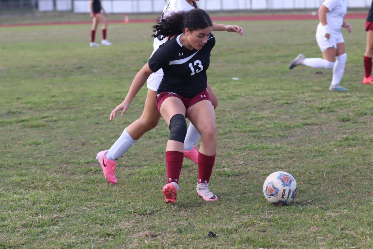 Midfield Amara Perovec (13) shields the ball from an opposing player during the second quarter. Perovec fought for the ball during the first half of the game, but was taken out of the game by her coach after fouling an opposing player. "I think I had some good defensive plays and throw balls, but my favorite game of the season was when we beat Boca High 5-0," Perovec said.