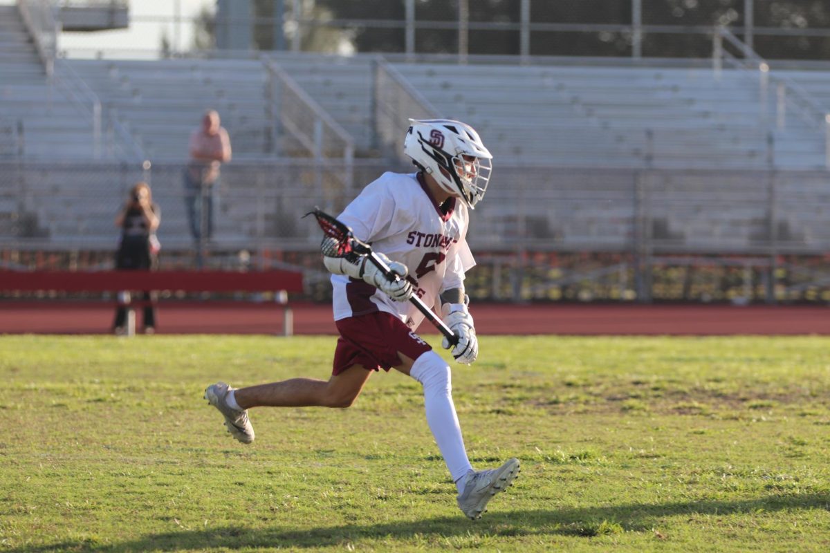 Captain of the MSD varsity lacrosse team Michael Cacace (5) drives down the field on Wednesday, Feb. 12, controlling the Eagles' offense. MSD lost their second game of the season 1-17 to the Community School of Naples Seahawks at Cumber Stadium; the team's point was scored by attacker Zaid Popen (43) in the first quarter of the game. "After each game there is improvement," Cacace said. "It only goes up from here."