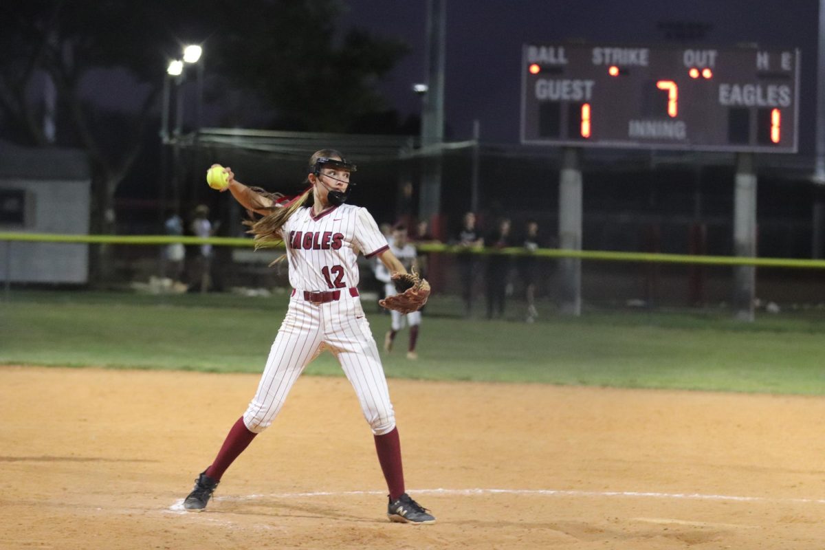 Pitcher Kaitlin Enright (12) stands on the pitcher's mound, winding up to pitch the ball to a Spanish River High School batter. This was in the seventh inning of MSD varsity softball's home game on Thursday, March 6, and Enright pitched throughout the entire game because the team's starting pitcher Addison Zajkowski (3) was out sick.