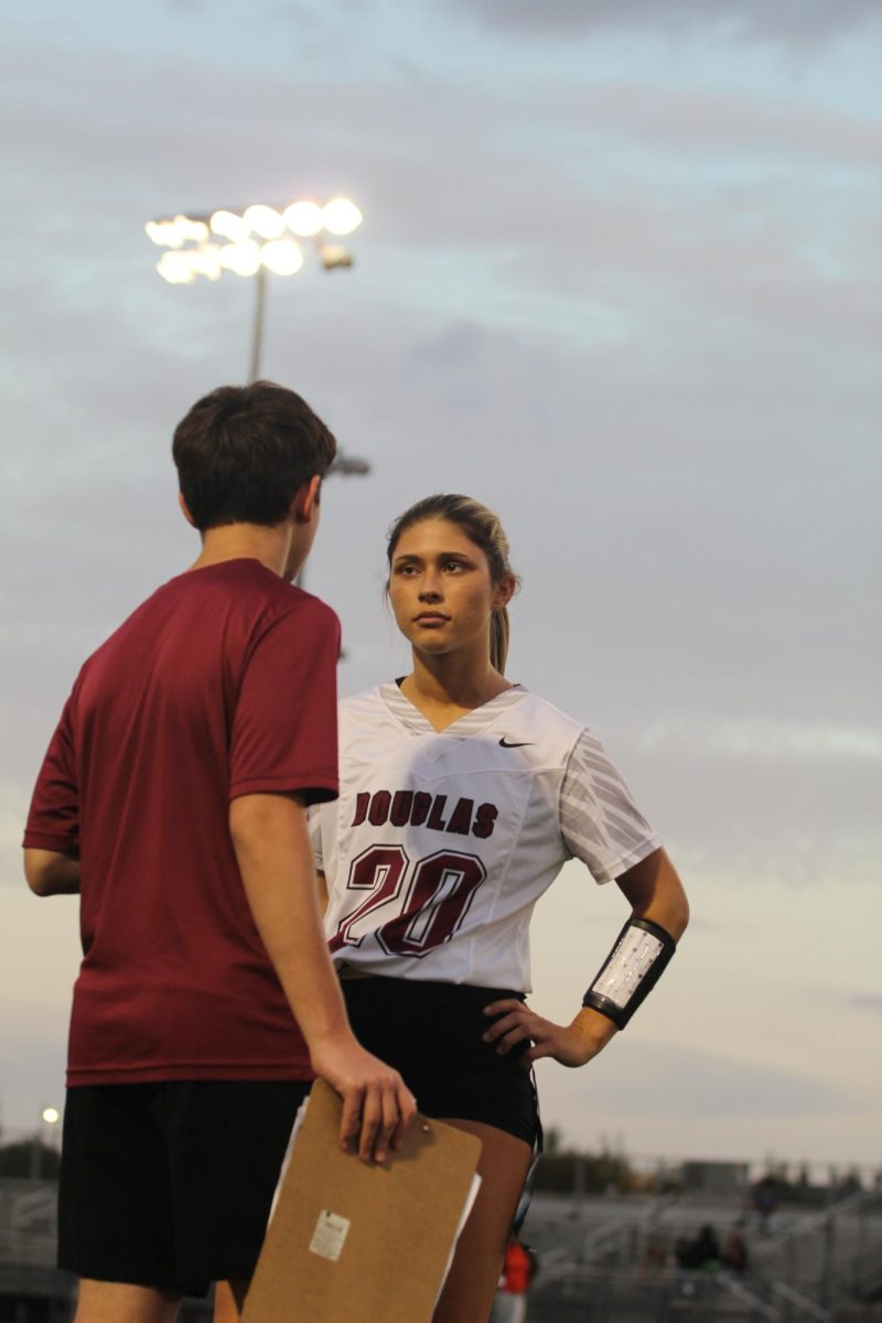 Wide receiver and safety Savannah Tenore (20) talks strategy with sophomore assistant coach Ben Goldman. Tenore has had five interceptions so far this season and has an average of 44 yards for each punt.